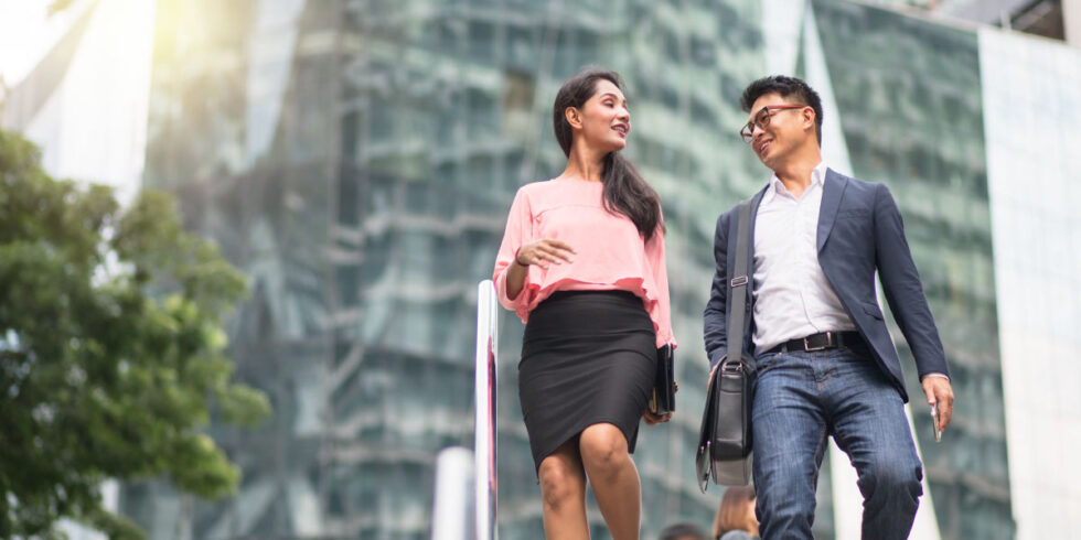 Two professionals speaking to each other as they walk through the city